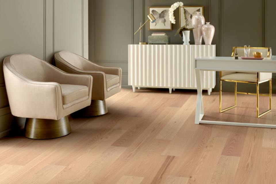 Light hardwood flooring in home office with gold and neutral accent furniture and decor.